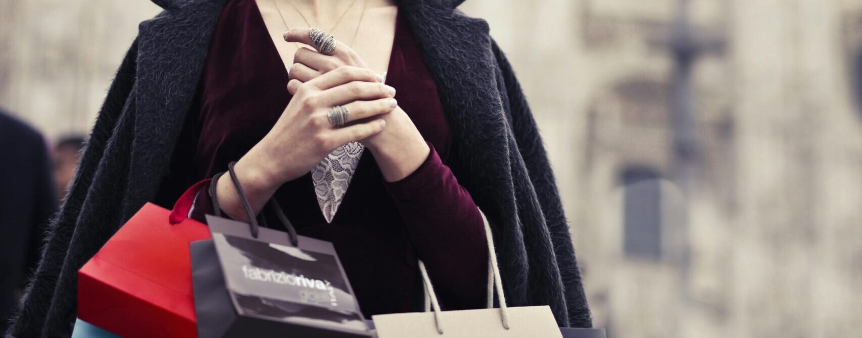 Fashionable woman holding shopping bags in front of Milano Cathedral in Italy.